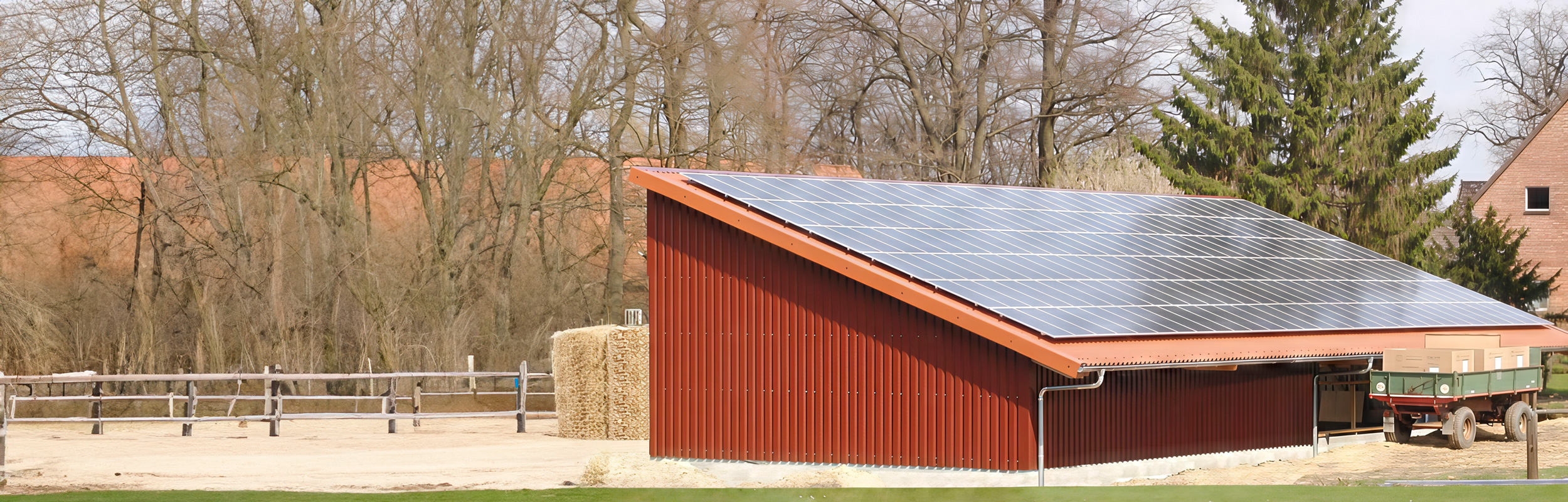 Landwirtschaftliche Halle mit roter Trapezblechfassade und großflächiger Photovoltaikanlage auf dem Satteldach.