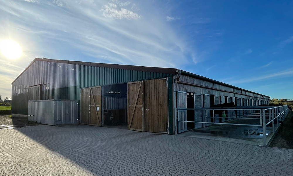 ußenansicht einer modernen landwirtschaftlichen Stallhalle in Holz- und Metallbauweise.