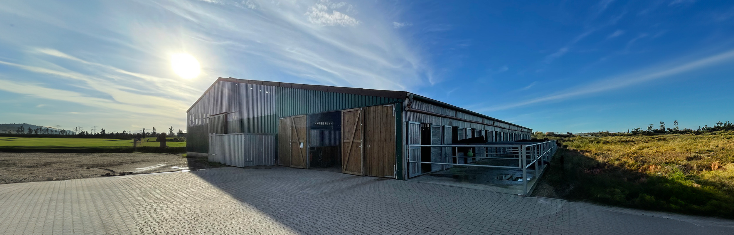 ußenansicht einer modernen landwirtschaftlichen Stallhalle in Holz- und Metallbauweise.