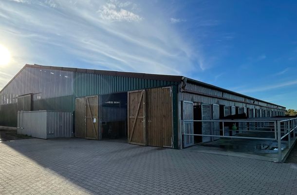 ußenansicht einer modernen landwirtschaftlichen Stallhalle in Holz- und Metallbauweise.