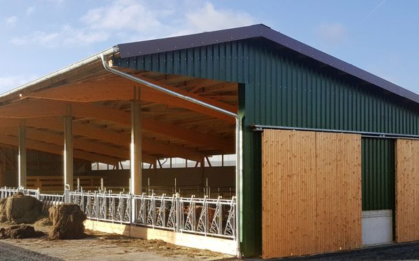 Offenstall mit grüner Holz- und Stahlkonstruktion im Sonnenschein